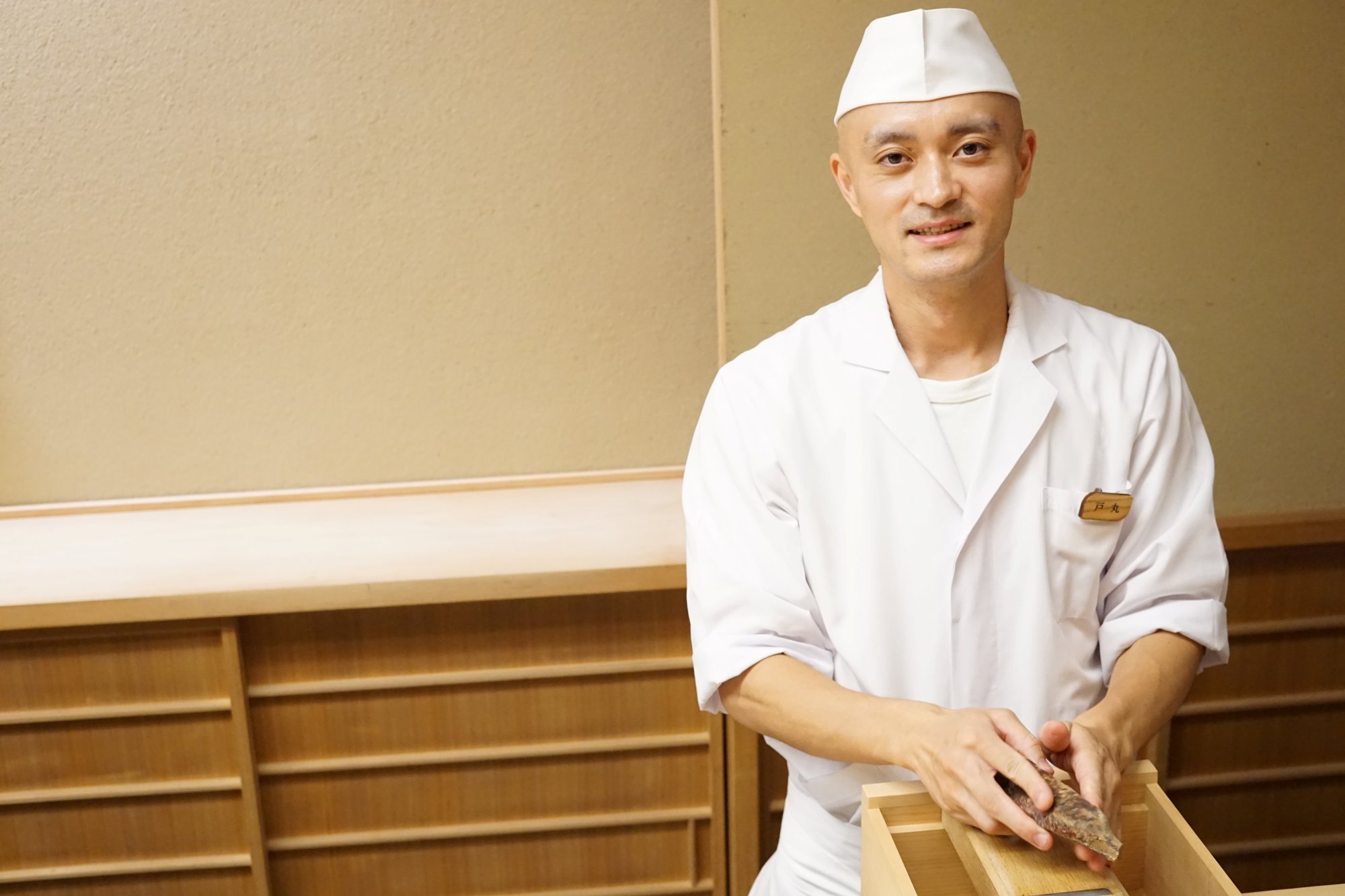 カウンターで鰹節を手に笑顔を見せる戸丸直貴さん
